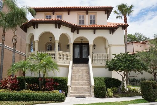 A white, two-story, Mediterranean-style home with palm trees and steps leading up to the front door. A white, two-story, Mediterranean-style home near where you can hire a Tampa property manager from Hoffman Realty