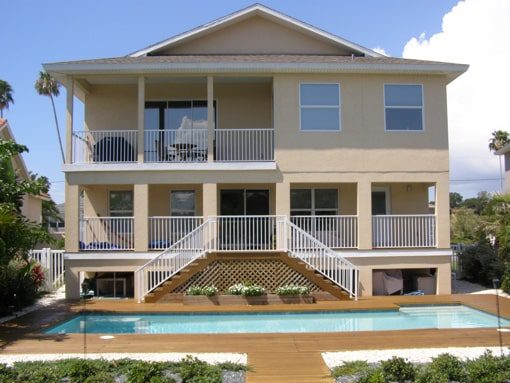 A beige two-story home with a pool and double staircase near where you can hire a Tampa property manager from Hoffman Realty