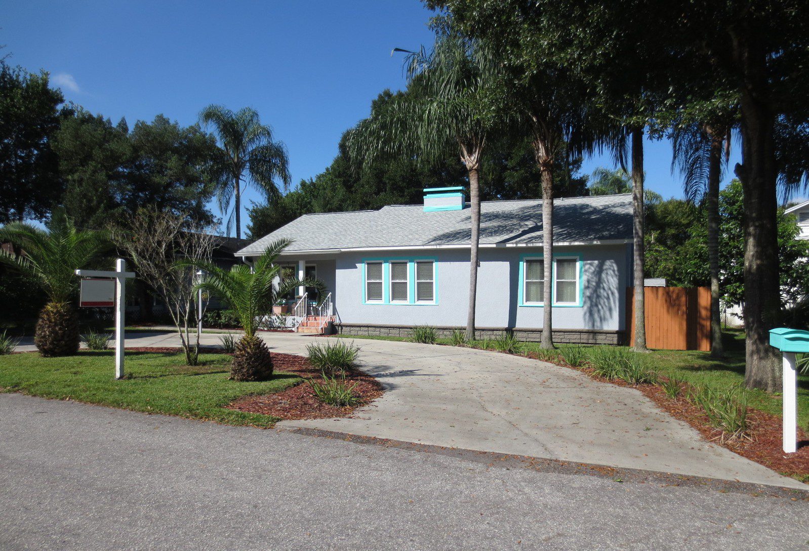 A long drive way leads to a lavender and turquoise framed house, near where Hoffman Realty offers Tampa real estate services