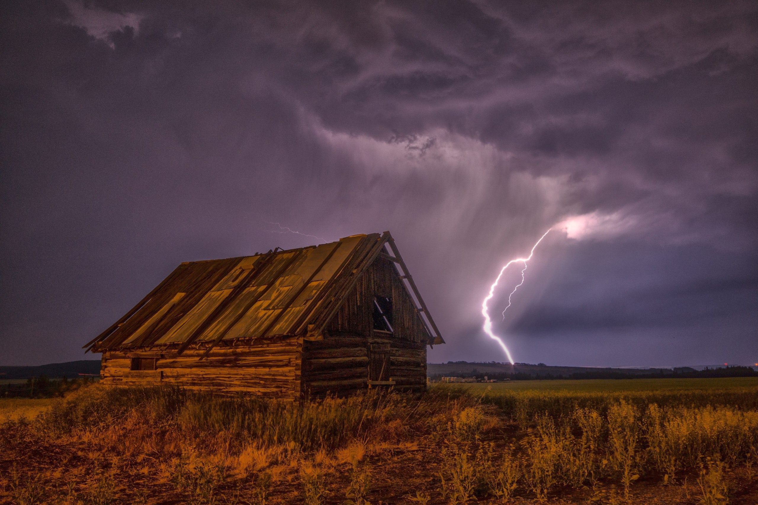 A house barn in a country side with purple clouds and lightning, which is like a representation of a Hoffman Realty's shutter installation