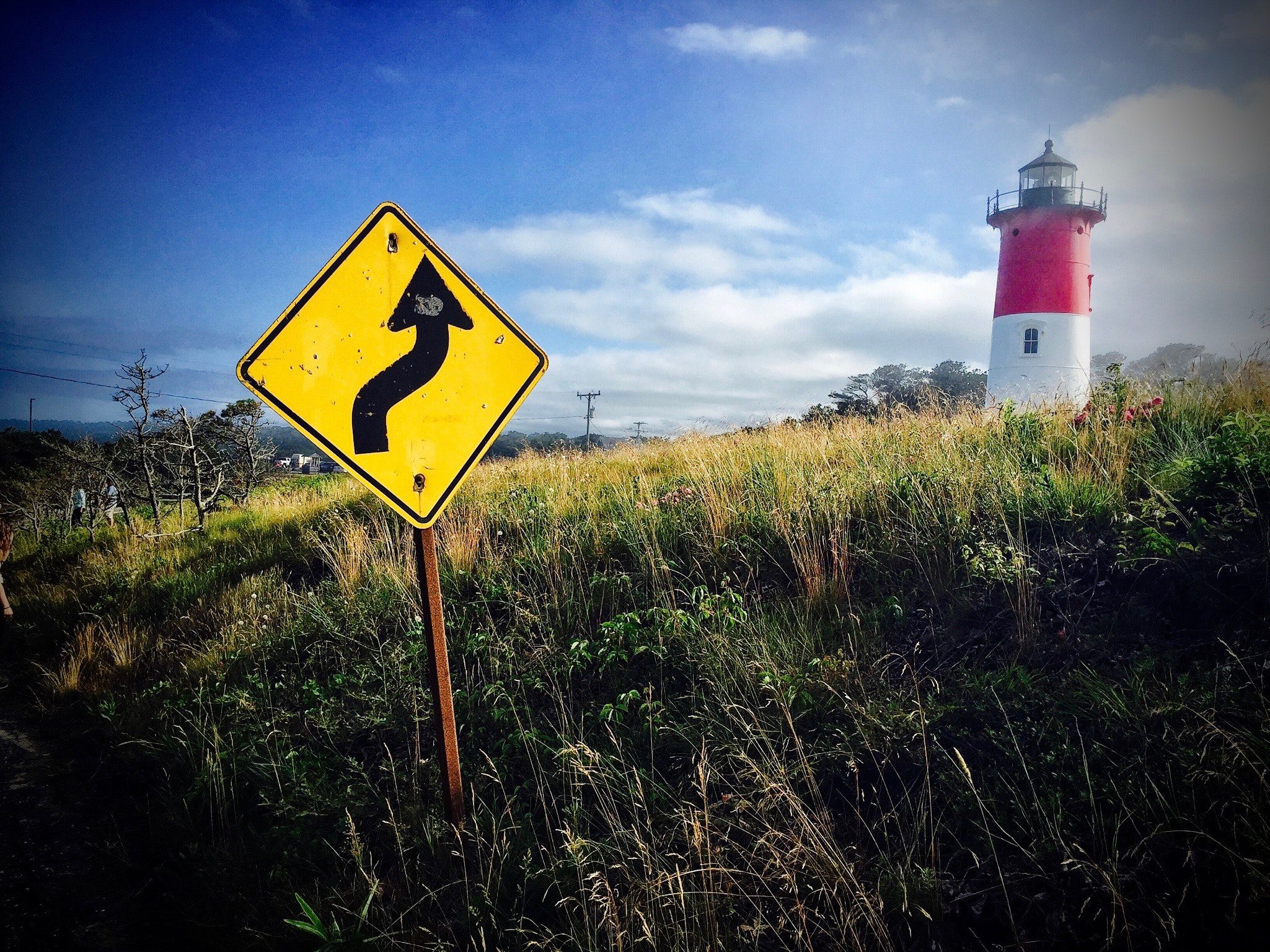 a caution sign in an uphill with lighthouse on top