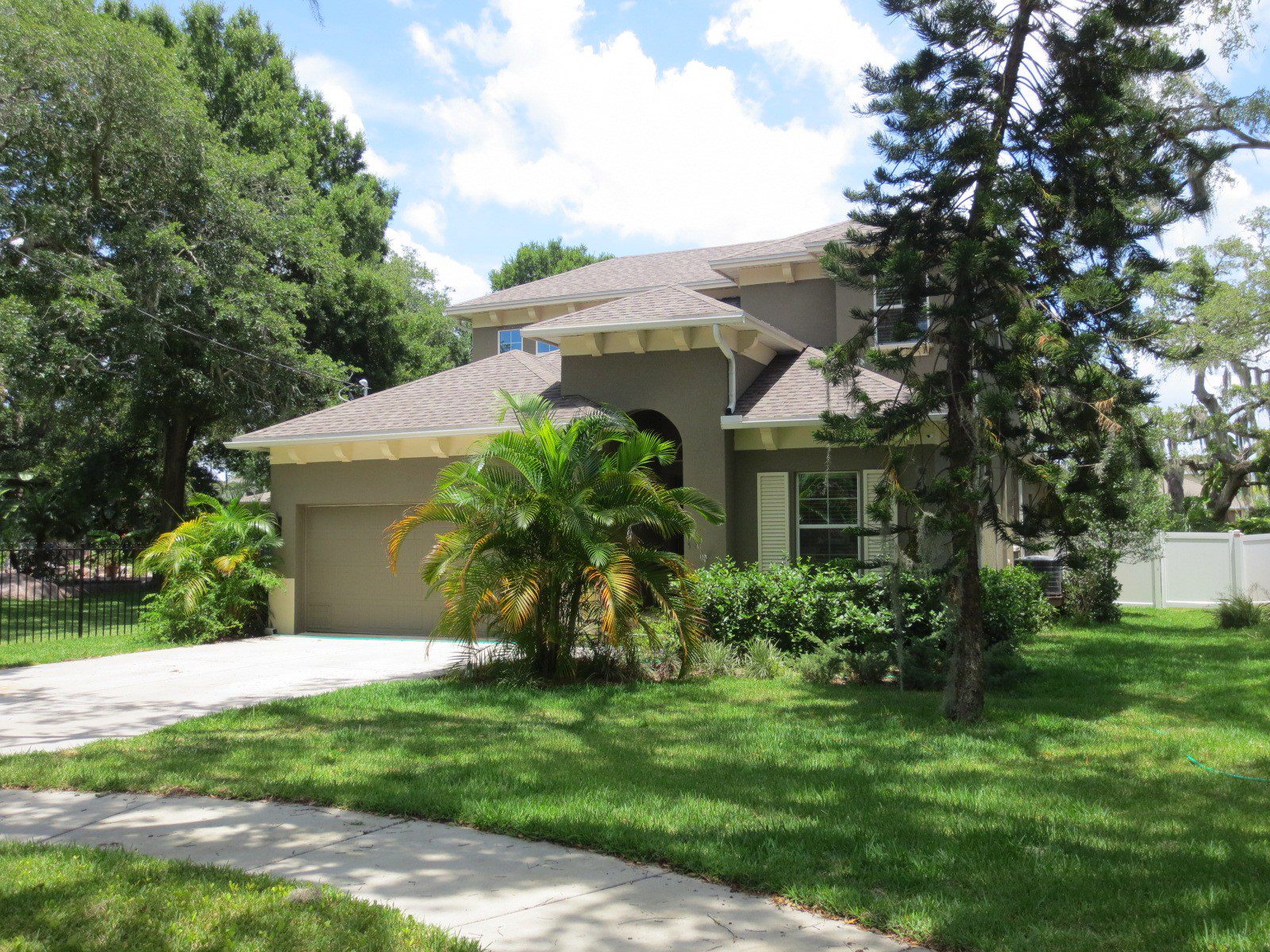 A dark gray house on a green lawn with trees, near where Hoffman Realty offers Tampa leasing service
