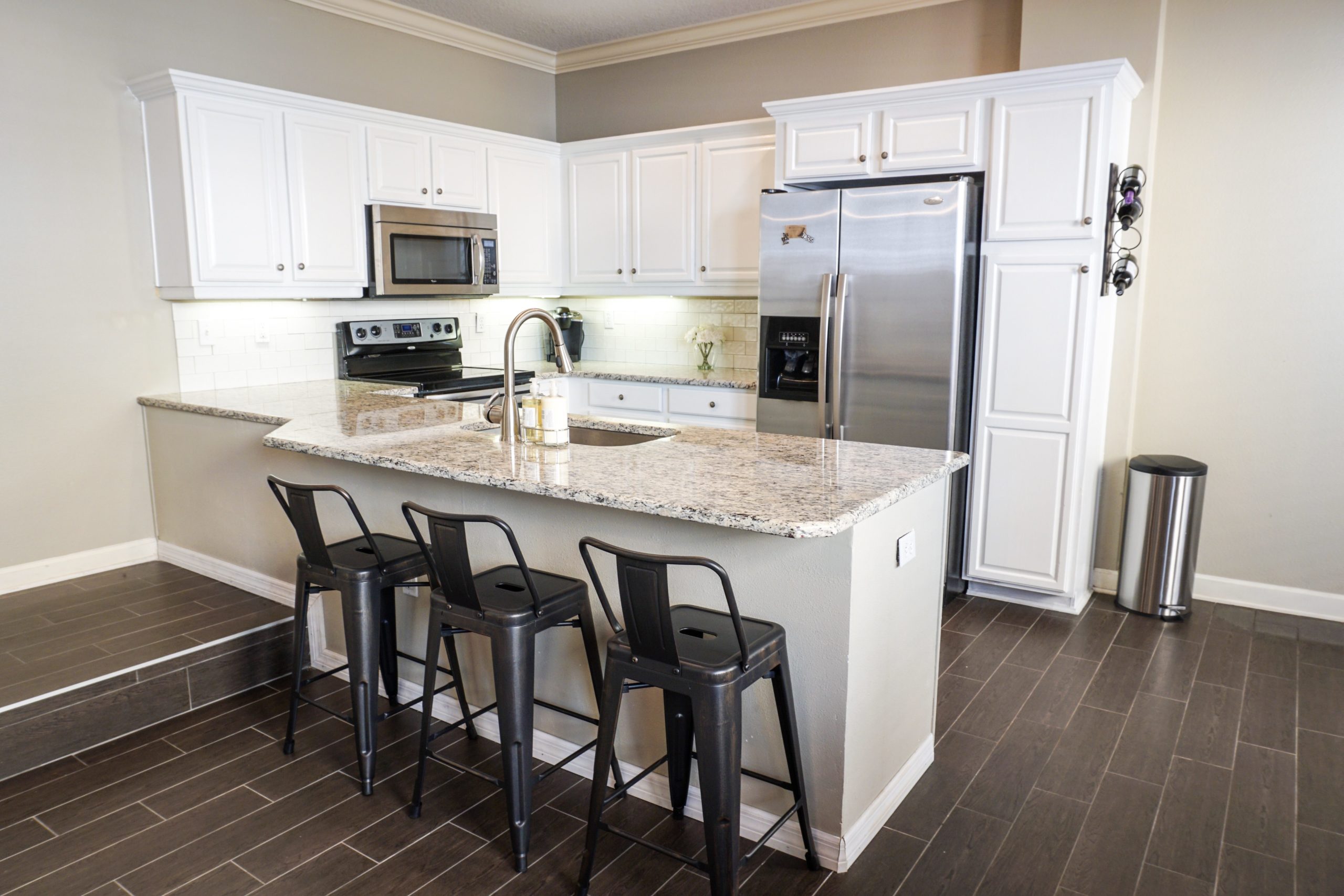 House kitchen area with stove, oven, refrigerator, sink, counter table and three high chair